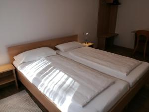 1 cama grande con sábanas blancas y almohadas. en Dorf-Zimmer Mirth, en Eltendorf