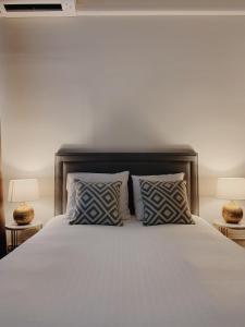 ein Schlafzimmer mit einem weißen Bett mit Kissen und 2 Lampen in der Unterkunft La Lys Rooms & Suites in Gent