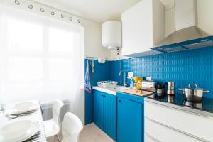 a blue kitchen with white cabinets and blue tiles at Le Studio Bleu de la gare in Vieux-Boucau-les-Bains