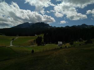a field with a fence and mountains in the background at Bosaca apartment in Žabljak +4 photos