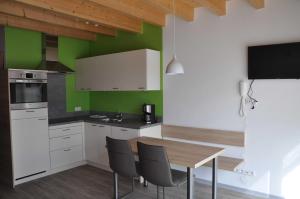 uma cozinha com armários brancos e uma mesa e cadeiras de madeira em Ferienwohnung Vollert em Willsbach
