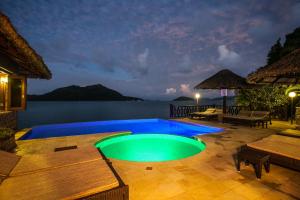 a swimming pool on a patio with a view of the water at Le Grand Bleu Villas in Baie Sainte Anne