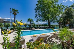 a pool at a resort with chairs and trees at Hotel Arcadia Locarno, a Trademark Collection by Wyndham in Locarno