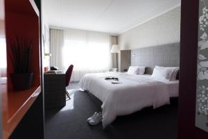 una habitación de hotel con una gran cama blanca y una ventana en pentahotel Kassel, en Kassel