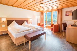a bedroom with a large bed and a desk and chairs at Bernerhof Swiss Quality Hotel in Kandersteg