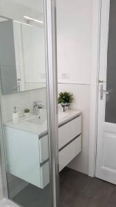 La salle de bains blanche est pourvue d'un lavabo et d'un miroir. dans l'établissement IL NIDO DELLA ZIA, à La Spezia