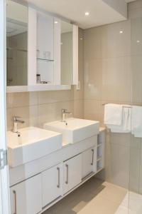 a white bathroom with two sinks and a mirror at Green Avenue Apartments in Gaborone