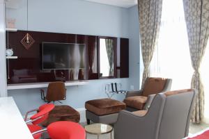 Green Avenue Apartments في غابورون: غرفة معيشة مع كراسي وتلفزيون بشاشة مسطحة