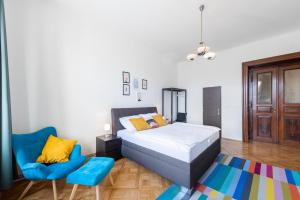 ein Schlafzimmer mit einem Bett und einem blauen Stuhl in der Unterkunft Residence Tesnov Apartment in Prag