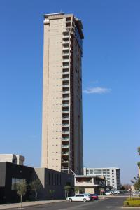 a tall building with cars parked in a parking lot at Green Avenue Apartments in Gaborone