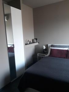 a small bedroom with a bed and a mirror at CameLia in Ivrea