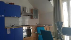 eine Küche mit blauen Schränken und einem Tisch mit Stühlen in der Unterkunft La Magnolia Apartments in Desenzano del Garda