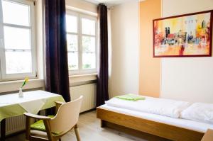 um quarto com uma cama, uma mesa e uma janela em Wallfahrts-Gaststätte Heilbrünnl em Roding