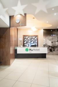 H+ Hotel Ried في ريد إم إنكرايس: لوبي الفندق مع وجود علامة الفندق علي الحائط