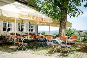 restauracja ze stołami i krzesłami pod drzewem w obiekcie Wallfahrts-Gaststätte Heilbrünnl w mieście Roding