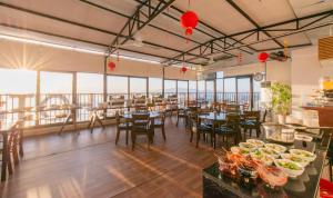 una sala da pranzo con tavoli, sedie e finestre di Bellevue Hotel a Nha Trang