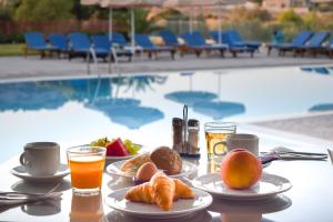 a table topped with plates of food next to a pool at Zoes Hotel & Suites in Faliraki
