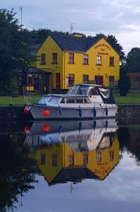 a boat sitting on the water in front of a yellow house at Nanny Quinn's Apartment in Killucan