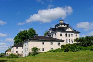 a large white building with a black roof on a field at Öster Malma vandrarhem in Nyköping