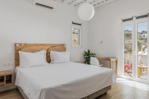 a white bedroom with a large bed and a window at Gazia Sea View House - Mykonos Town in Mýkonos City