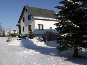 a white house in the snow with a tree at Ferienwohnung Hauptmann in Frauenwald
