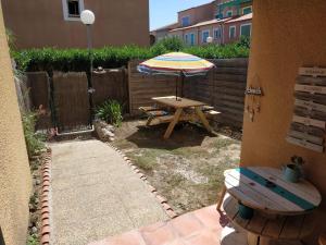 eine Terrasse mit einem Picknicktisch und einem Sonnenschirm in der Unterkunft Résidence Village Marin Catalan TORREILLES PLAGE in Torreilles