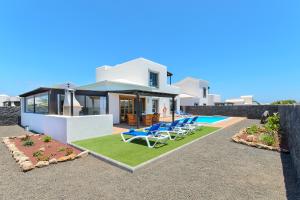 une villa avec une piscine et des chaises longues dans l'établissement Hipoclub Villas, Aguamarina 29, à Playa Blanca