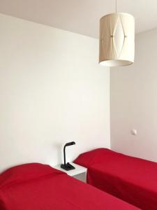 two beds in a room with red sheets and a lamp at InPorto in Porto