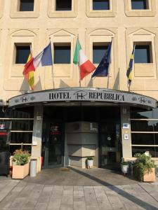 Un bâtiment avec des drapeaux à l'avant dans l'établissement HR Hotel, à Monfalcone