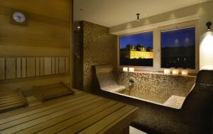 Habitación con bañera y ventana con reloj. en Hotel Maribor & Garden Rooms en Maribor