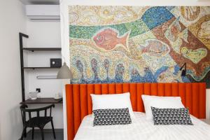 ein Schlafzimmer mit einem orangefarbenen Kopfteil und einer farbenfrohen Wand in der Unterkunft SV Hotel in Wladiwostok