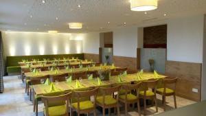 une grande salle à manger avec des tables et des chaises jaunes dans l'établissement Ferienhof Laurentius, à Oedheim
