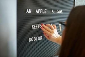 a woman is writing an apple a day on a mirror at Hotel Metropol by Maier Privathotels in Munich