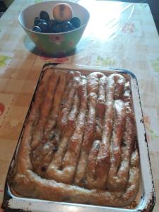 a pan of sausages on a table with a bowl of fruit at Bosaca apartment in Žabljak