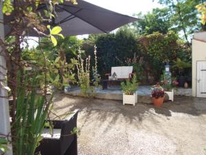 a patio with an umbrella and potted plants at les mésanges in La Grève-sur-Mignon