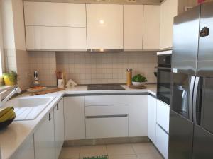 una cucina con mobili bianchi e un frigorifero in acciaio inossidabile di Apartment Blue Infinity 3 LeMi a Zaton