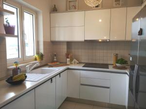 una cucina bianca con mobili bianchi e un lavello di Apartment Blue Infinity 3 LeMi a Zaton
