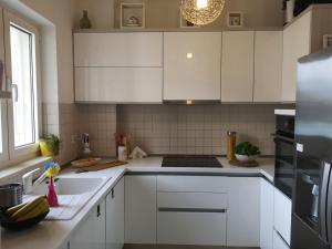una cucina con mobili bianchi e un frigorifero nero di Apartment Blue Infinity 3 LeMi a Zaton Altre 21 foto