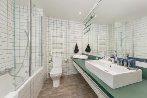 a bathroom with a sink and a tub and a toilet at Center Parcs Les Bois Francs in Verneuil d'Avre et d'Iton