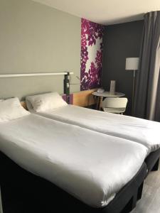 a large white bed in a room with a table at ibis Laon in Laon
