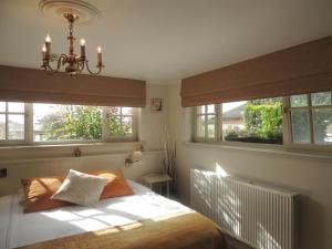 ein Schlafzimmer mit einem Bett mit zwei Fenstern und einem Kronleuchter in der Unterkunft Bed & Breakfast Het Zilte Zand - Westende - Middelkerke - De Kust in Middelkerke