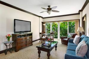 ein Wohnzimmer mit einem blauen Sofa und einem TV in der Unterkunft Waipouli Beach Resort Beautiful Luxury Ground Level Garden View AC Pool! in Kapaa