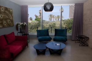 salon z czerwoną kanapą i niebieskimi krzesłami w obiekcie Liber Apartments BY RAPHAEL HOTELS w Tel Awiwie