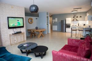 a living room with a couch and a tv on a wall at Liber Apartments BY RAPHAEL HOTELS in Tel Aviv