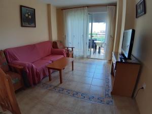 ein Wohnzimmer mit einem Sofa, einem TV und einem Tisch in der Unterkunft Urbanización Sueños de Denia II apto 2 habitaciones in Denia