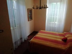 a bedroom with a striped bed with two windows at Agritur Tenno Bio Natura in Tenno +15 photos