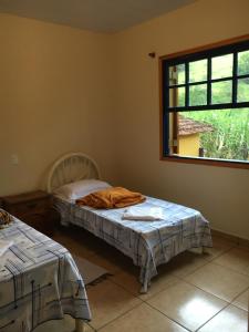1 dormitorio con 2 camas y ventana en Quinta dos Paiva: horta natural e sossego, en Monte Alegre do Sul