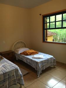 a bedroom with two beds and a window at Quinta dos Paiva: horta natural e sossego in Monte Alegre do Sul