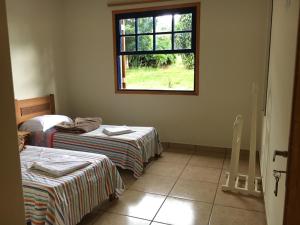 um quarto com duas camas e uma janela em Quinta dos Paiva: horta natural e sossego em Monte Alegre do Sul
