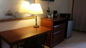 a desk with a lamp and a dresser in a bedroom at Lake Side Lodge in Lake Worth